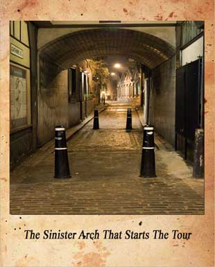 Looking through the arch into a cobbled, dark, alleyway.