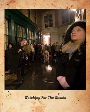 A group of ghost walkers look up at the haunted window.